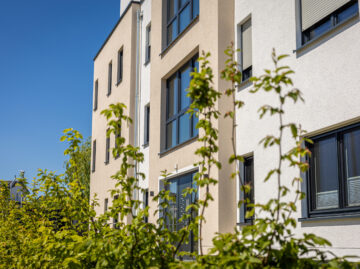 modern-residential-building-exterior-with-green-foliage-clear-blue-sky
